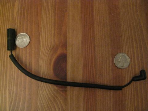 1994 Ford Probe - A single spark plug wire is shown next to two quarters on a wooden table.