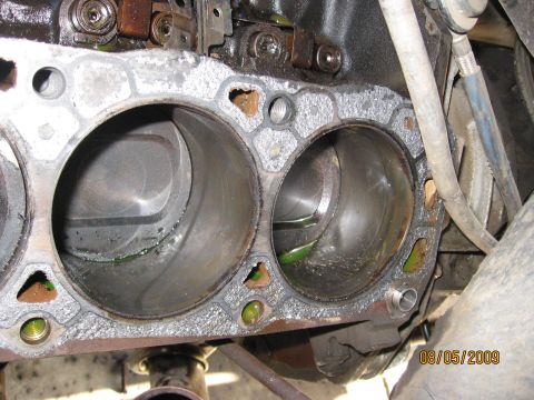 1994 Ford Bronco - Close-up of an engine block's cylinders, showing a damaged gasket and green fluid residue.