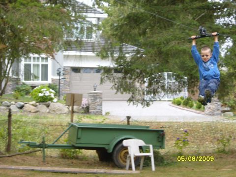 1989 Ford Bronco - A child rides a zip line in a yard with a green trailer and a house in the background.