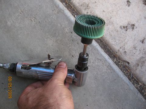 1994 Ford Bronco - A hand grips a metal angle grinder with a green abrasive disc, positioned over a concrete surface.