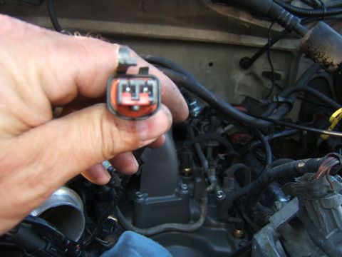 1988 Ford Bronco - A hand holds an electrical connector near the engine bay, showing various wires and engine parts.