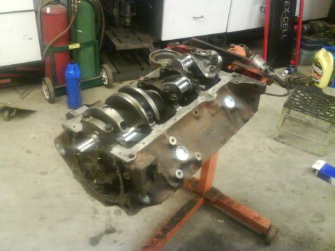 1984 Chevrolet Blazer - Engine block with crankshaft visible, mounted on an orange engine stand in a workshop.