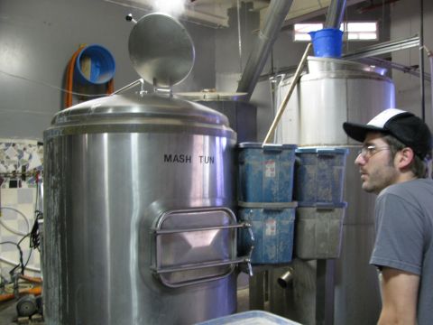 1985 Ford LTD Crown Victoria - A man observes a large stainless steel mash tun in a brewery during a brew day.