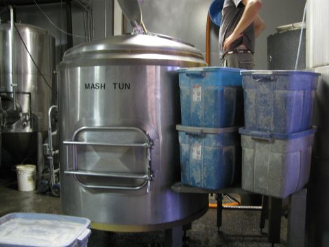 1985 Ford LTD Crown Victoria - Industrial brewing equipment, including a mash tun and storage containers, is shown in a dimly lit facility.