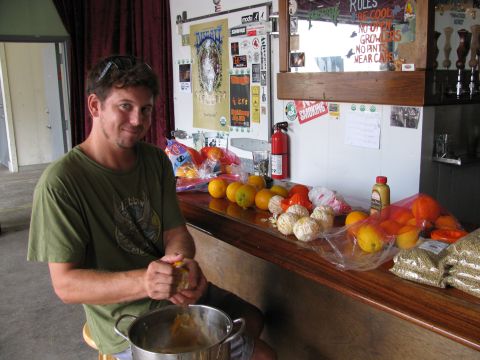 1985 Ford LTD Crown Victoria - A man peels oranges at a bar counter, with various fruits and bags of grain laid out.