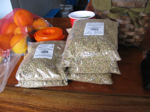1985 Ford LTD Crown Victoria - Several bags of coriander seeds and a mesh bag of oranges are displayed on a wooden surface, with a basket in the background.