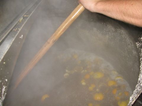 1985 Ford LTD Crown Victoria - A large pot is filled with steaming liquid and orange peels, being stirred by a wooden paddle during a brew day.