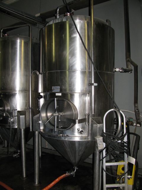 1985 Ford LTD Crown Victoria - Industrial fermentation tanks are shown in a dimly lit room, likely a brewery or similar facility.
