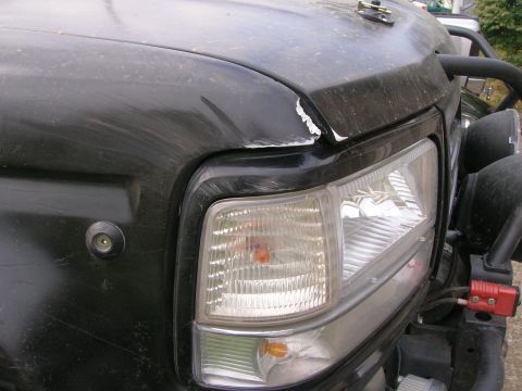 1996 Ford Bronco - Close-up of a black SUV's front fender and headlight assembly, showing some wear and tear.