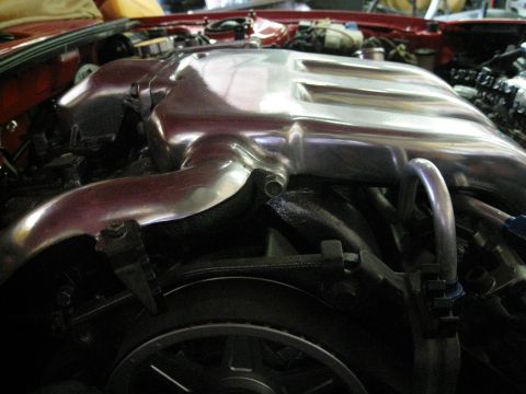 1994 Ford Probe - Close-up of a shiny intake manifold within a red vehicle's engine compartment.