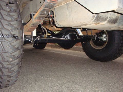 1989 Ford Bronco - Undercarriage view of a vehicle's rear axle, suspension, and large off-road tires.