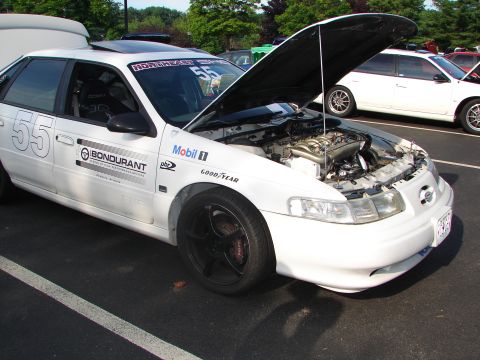1992 Ford Taurus - White 1992 Ford Taurus with racing decals and hood open, parked next to another white car.