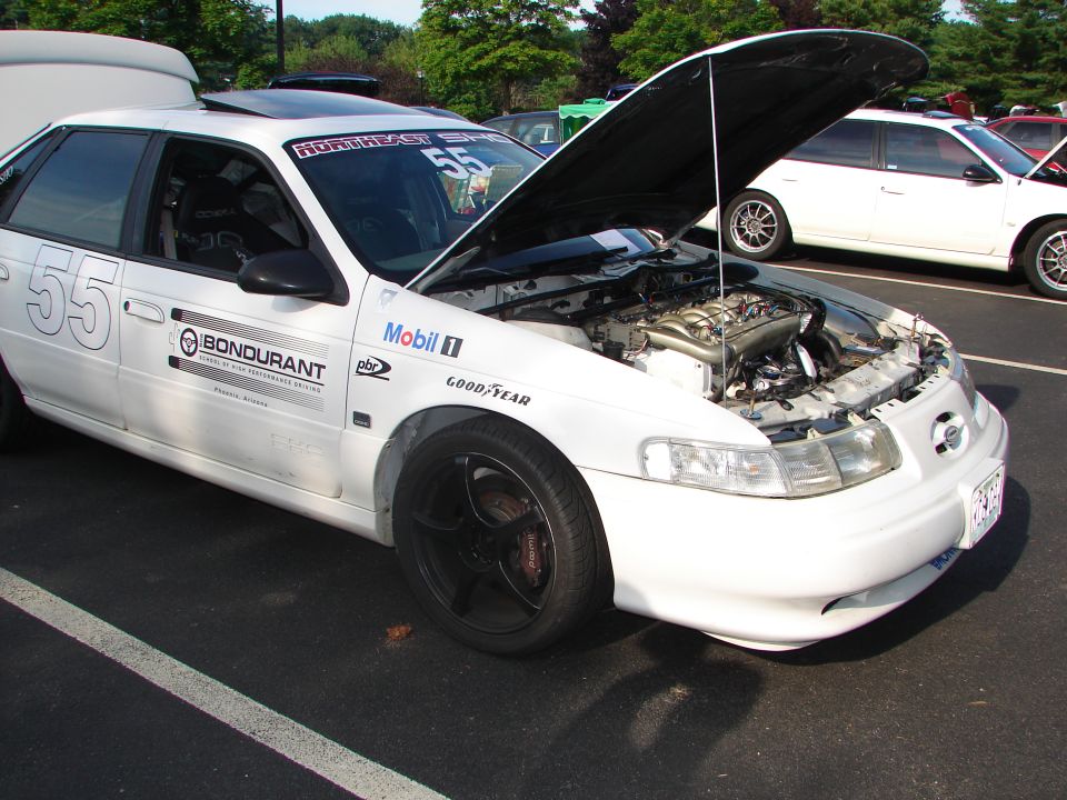 White 1992 Ford Taurus with racing decals, hood open, showing engine