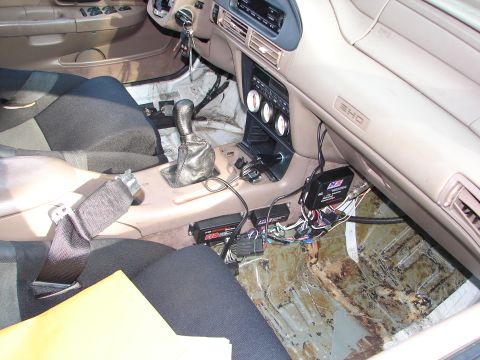 1992 Ford Taurus - The interior of a 1992 Ford Taurus shows aftermarket electronics and gauges installed on the center console and floor.