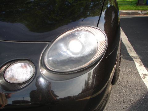 1992 Ford Taurus - The front corner of a black car is visible, focusing on the headlight and fog light assembly.