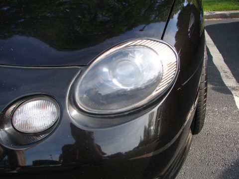 1992 Ford Taurus - Close-up of a black car's front headlight and fog light assembly.