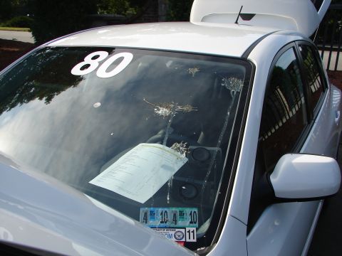 1992 Ford Taurus - Windshield of a white car with a large '80' sticker and evidence of bird droppings.