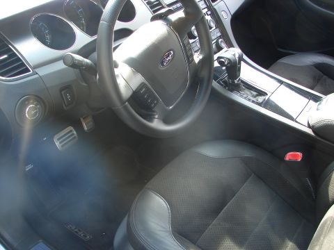 1992 Ford Taurus - Interior view of a black car with perforated seats and a Ford steering wheel.