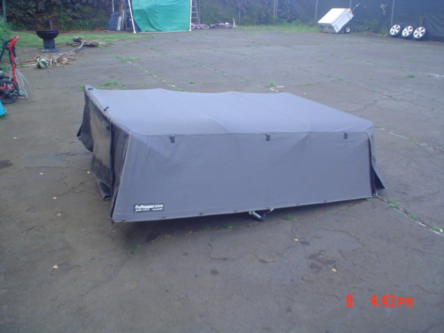 Gray Softopper soft-top cover with branding sitting on pavement outdoors