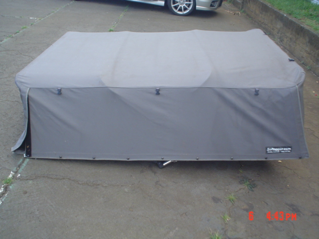 Gray Softopper soft truck bed topper folded on a driveway