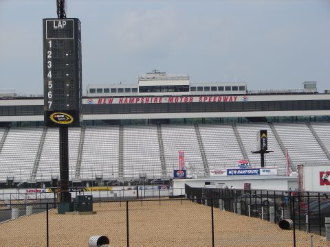 1992 Ford Taurus - The grandstands of New Hampshire Motor Speedway are visible behind a lap timing tower and fencing.