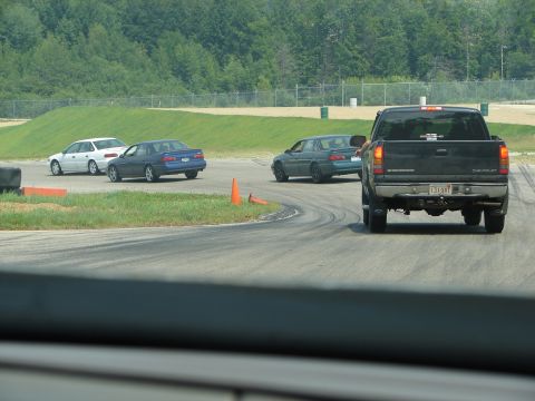 1992 Ford Taurus - Multiple vehicles are seen on a race track with trees in the background.