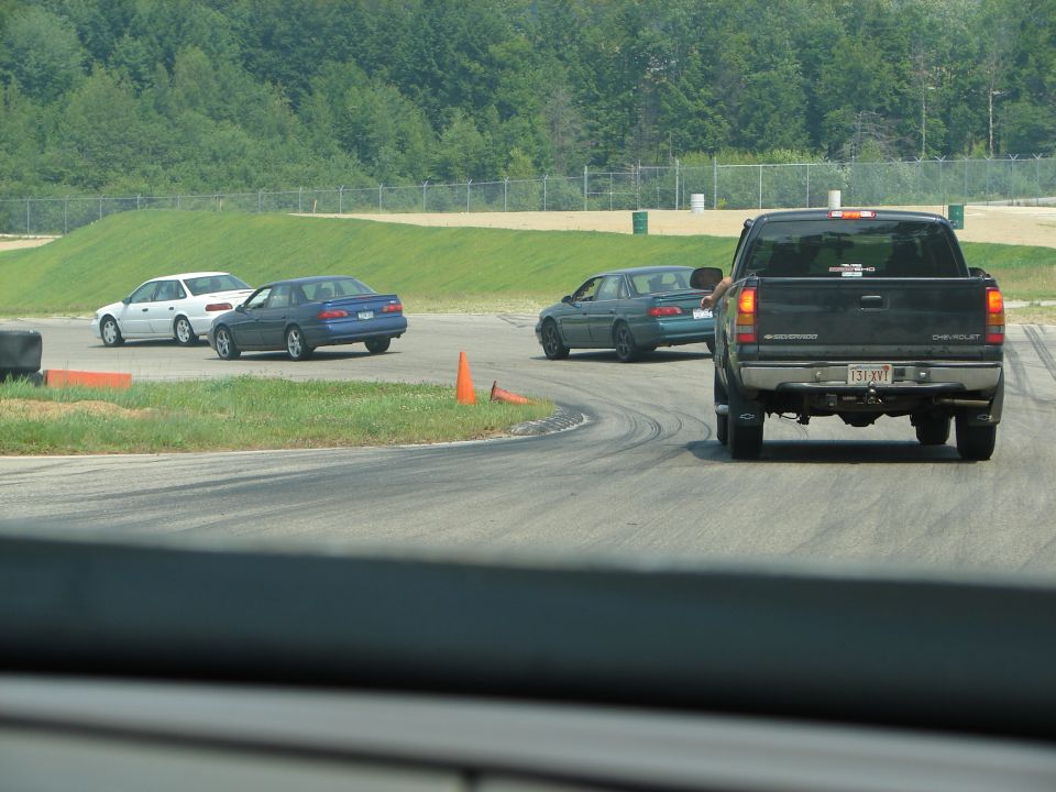 Black pickup truck and blue and white sedans on a race track