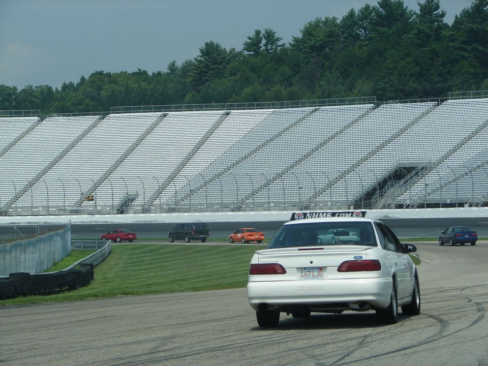 White 1992 Ford Taurus sedan from rear, on a race track with grandstands