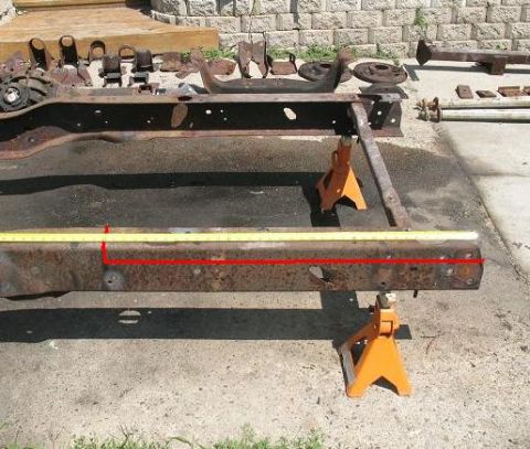 1978 Ford Bronco - A heavily rusted vehicle frame is supported by orange jack stands, with a yellow measuring tape and red line highlighting a section.
