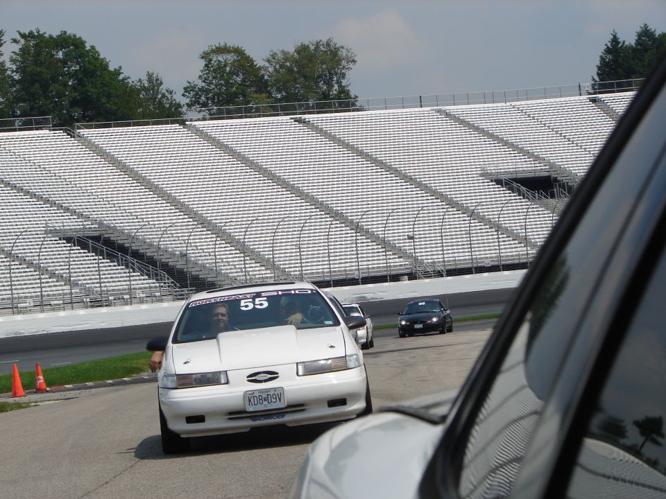 White 1992 Ford Taurus with racing number 55 on the windshield, driving on a track
