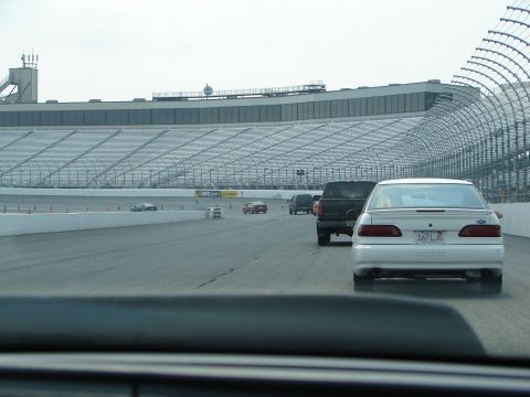 1992 Ford Taurus - A white 1992 Ford Taurus is seen from behind on a racetrack, with a stadium in the background.