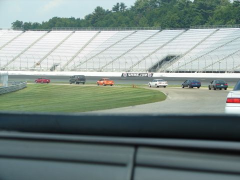 1992 Ford Taurus - Multiple vehicles are seen on a race track with large grandstands in the background.