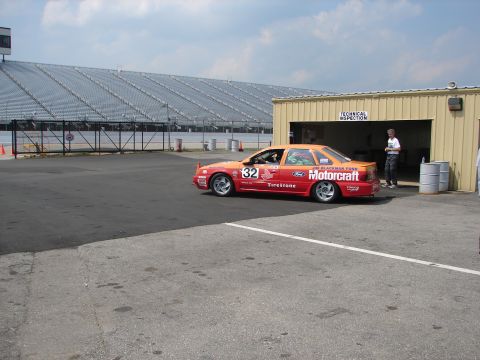 1992 Ford Taurus - A race car with "Motorcraft" sponsorship and the number 32 is parked near a building at a racetrack.