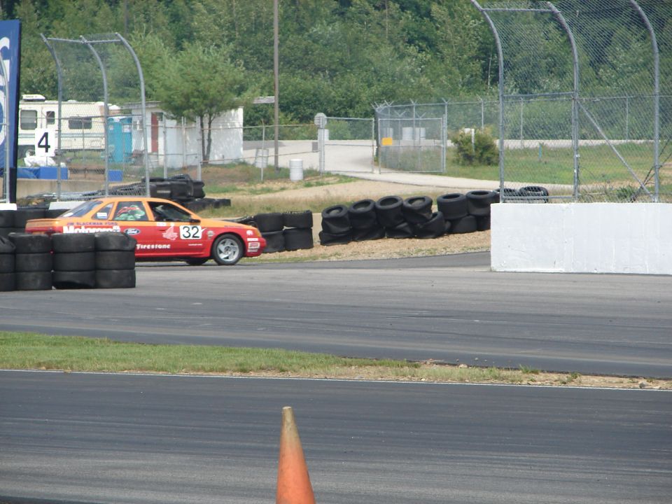 race car with number 32 on track, tires stacked on side