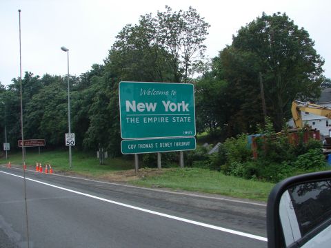 1992 Ford Taurus - A sign welcomes visitors to New York, with a construction site visible behind it.