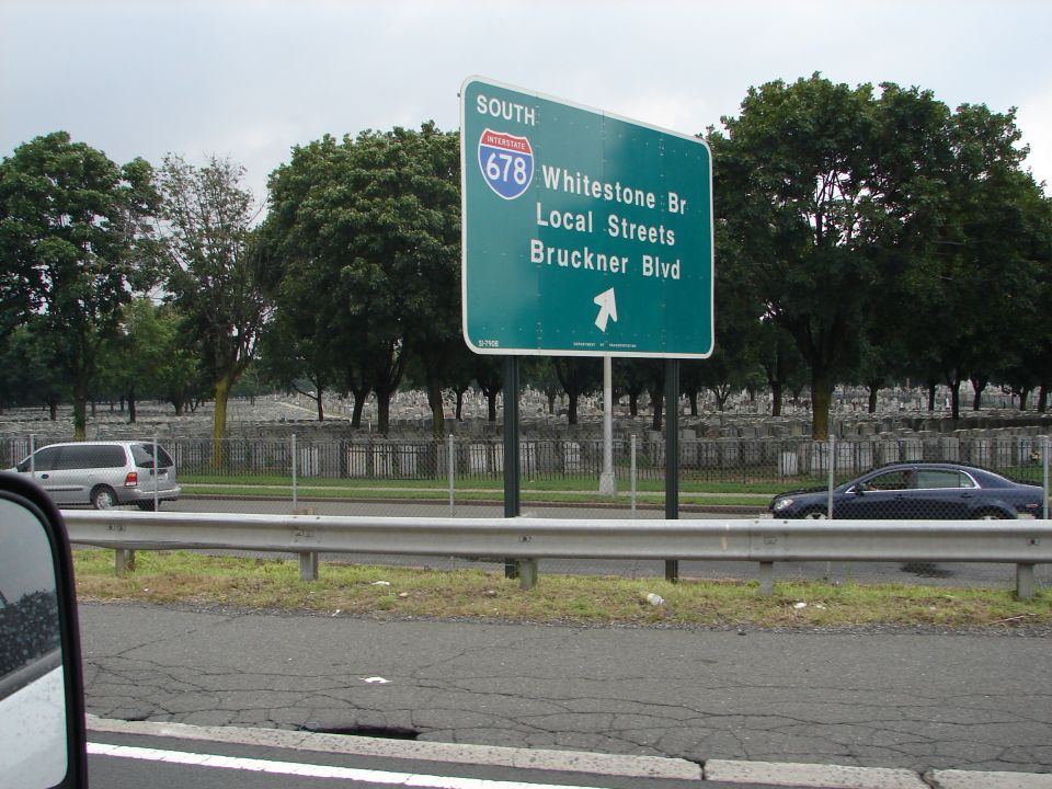 Highway sign for I-678 South, Whitestone Br, Local Streets, Bruckner Blvd. Silver minivan and dark sedan on highway