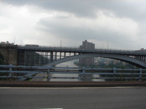 1992 Ford Taurus - A view of a bridge spanning a river under a cloudy sky, with buildings visible on the far bank.
