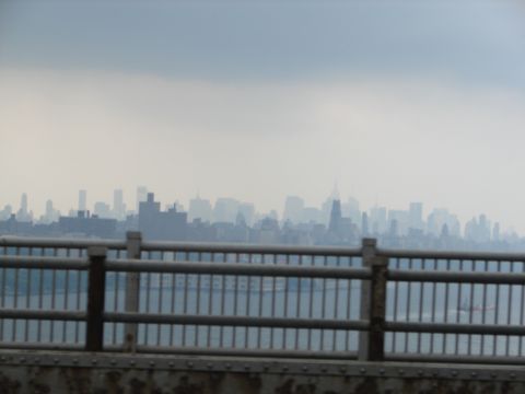 1992 Ford Taurus - A hazy city skyline is visible across the water, viewed from a bridge with a metal railing.