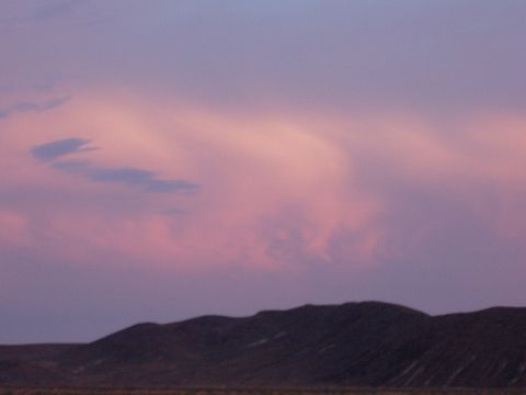 1992 Ford Taurus - The sky displays a beautiful gradient of pink and purple hues during sunset, casting shadows over the rolling hills below.