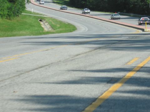 1991 Ford Crown Victoria - Several cars, including what appear to be police cruisers, travel along a winding road.