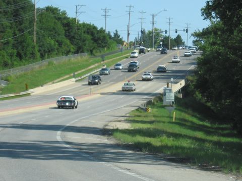 1991 Ford Crown Victoria - A police car is seen driving on a highway with other vehicles.