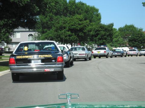 1991 Ford Crown Victoria - Several police cars, including a 1991 Ford Crown Victoria, are lined up on a residential street.