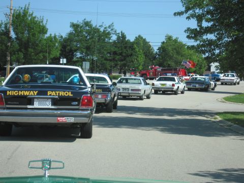 1991 Ford Crown Victoria - A procession of law enforcement vehicles, including a Highway Patrol car, moves down a suburban street.