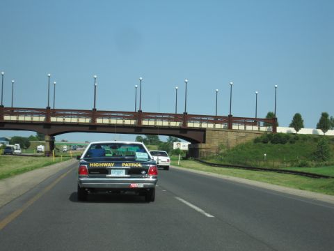 1991 Ford Crown Victoria - A 1991 Ford Crown Victoria, marked as a Highway Patrol vehicle, drives on a highway under a bridge.