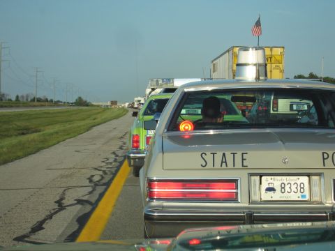 1991 Ford Crown Victoria - Traffic jam on highway with multiple vehicles including a state police car and a green pickup truck.