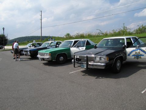 1991 Ford Crown Victoria - Several police cars, including a 1991 Ford Crown Victoria, are parked in a lot on a cloudy day.
