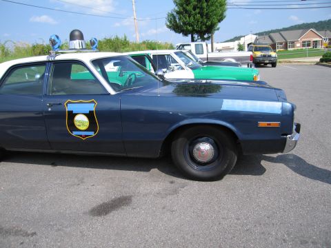 1991 Ford Crown Victoria - A police car is parked in a lot next to other vehicles under a clear sky.