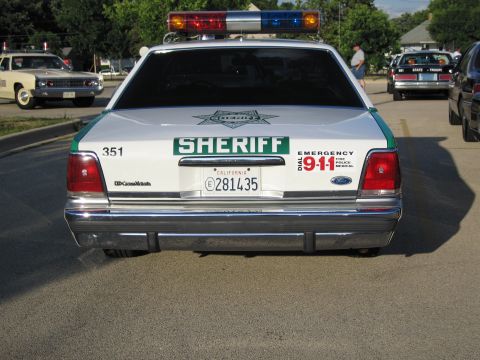 1991 Ford Crown Victoria - Rear view of a 1991 Ford Crown Victoria police car with "SHERIFF" markings and emergency decals.