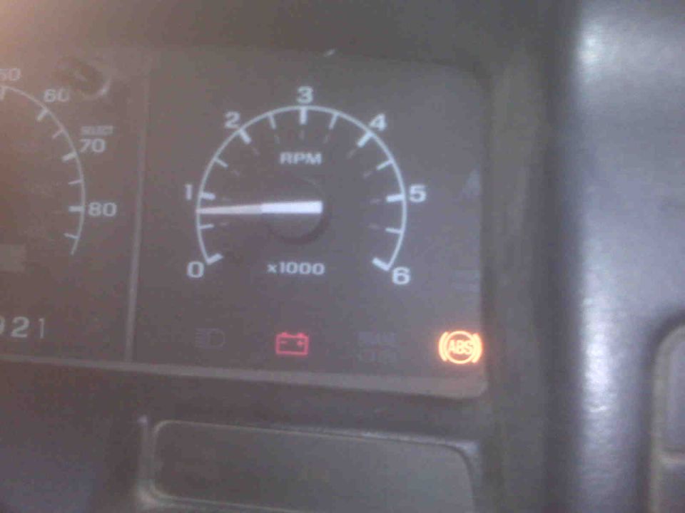 Dashboard gauges showing RPM and speed, with ABS and battery warning lights illuminated