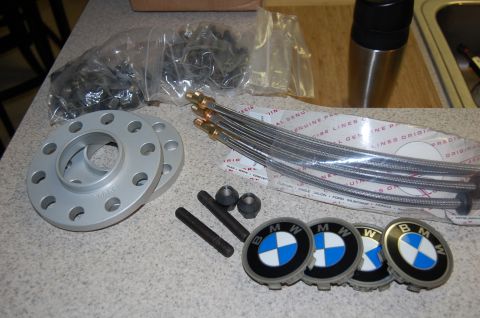 2002 BMW M3 - Various BMW parts including wheel spacers, lug bolts, and emblems are displayed on a countertop.